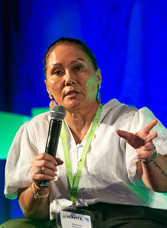 A woman in a white shirt addresses an audience